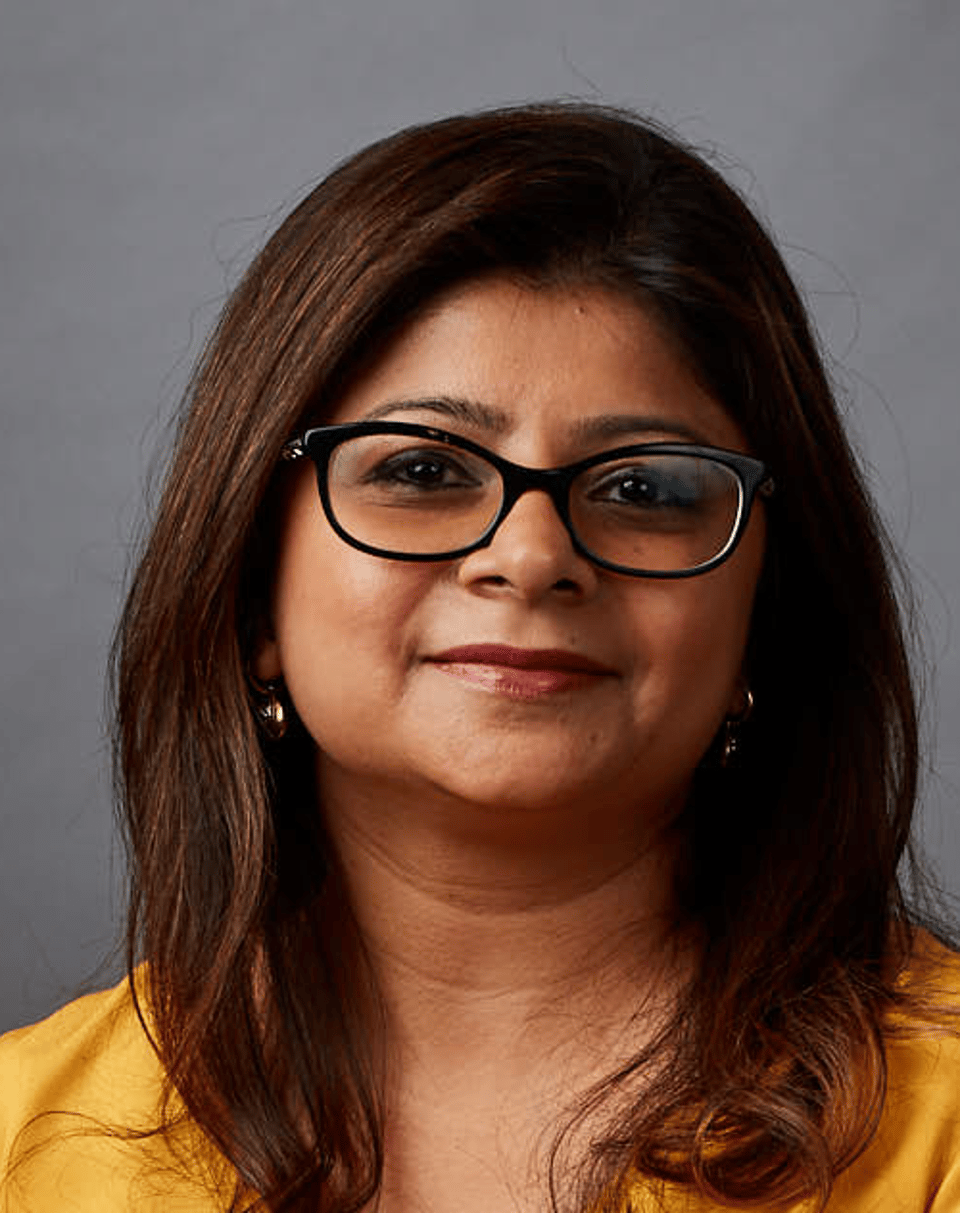 a woman wearing glasses and smiling at the camera